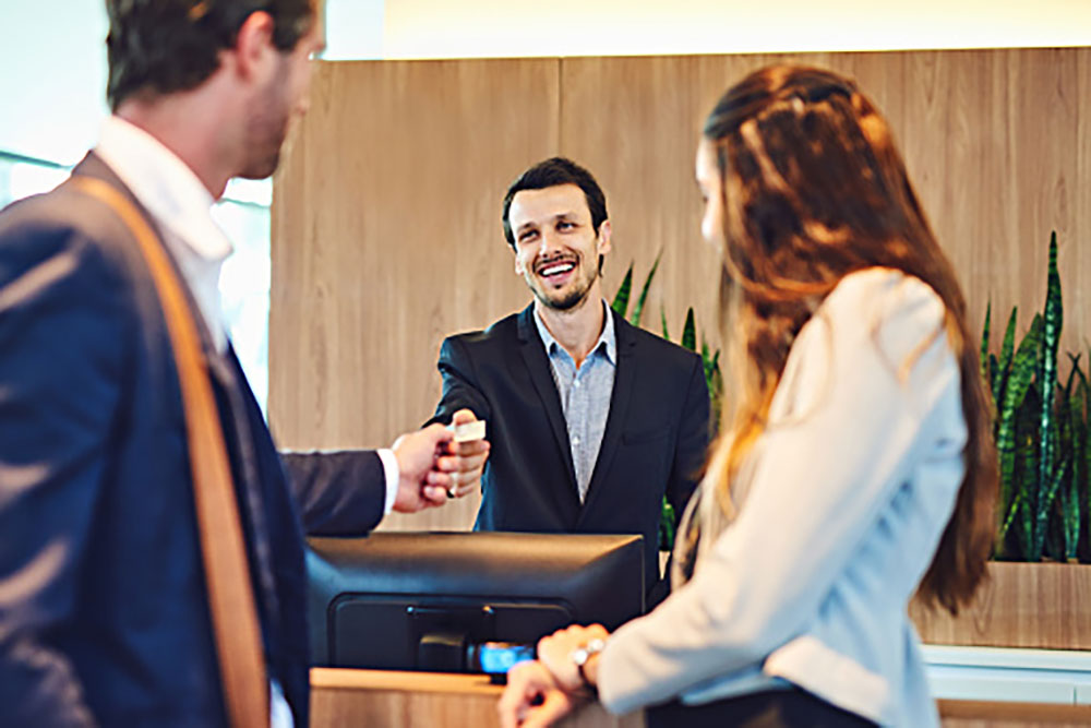 Front Desk Hotel Management Staff Greeting Couple Checking In